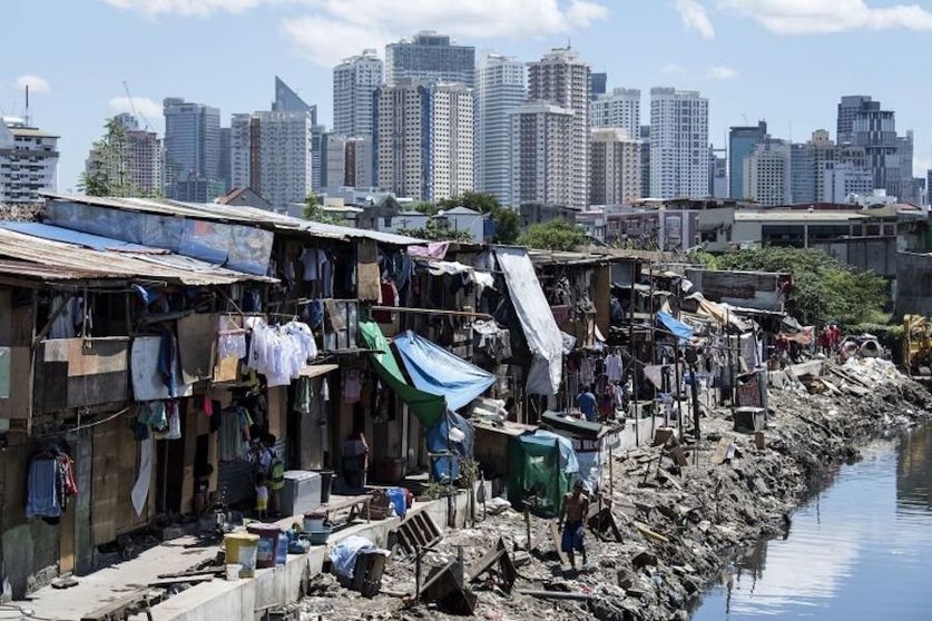 TOPSHOT - People living in a settlement walk about, as the skyline of Manila's financial district is seen in the background, on August 17, 2017. 
The Philippine economy grew by 6.5 percent in the three months to June, likely one of the fastest in Asia, the government said on August 17, defying concerns over President Rodrigo Duterte's unconventional leadership. / AFP PHOTO / Noel CELIS        (Photo credit should read NOEL CELIS/AFP/Getty Images)